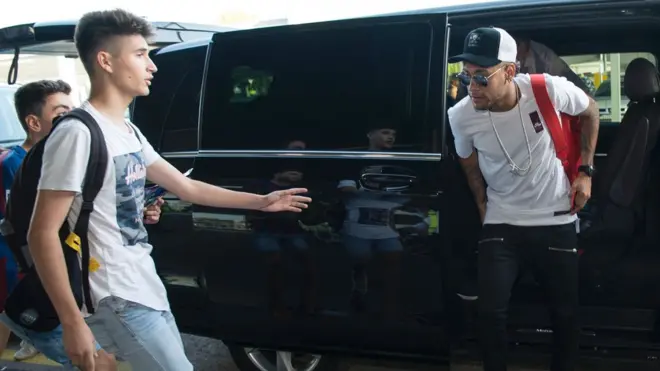 Neymar ke luar dari mobil di bandara Barcelona untuk menuju Paris, 4 Agustus, bergabung dengan Paris St-Germain.