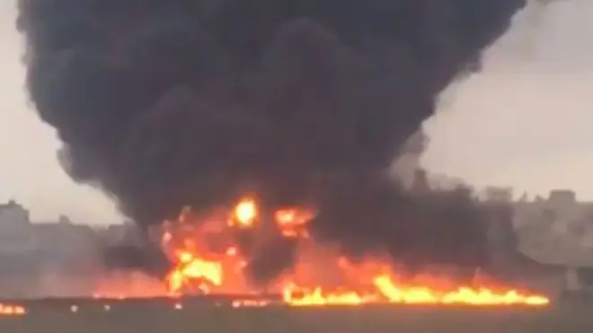 screengrab of eyewitness video, showing thick plume of black smoke rising from orange flames