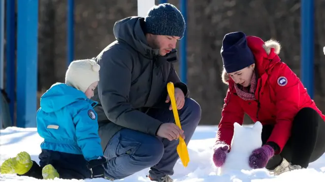 أب وأم وطفل يصنعون أشكالا من الثلج في موسكو