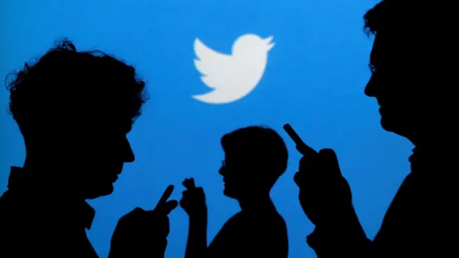 Twitter logo with silhouettes of people looking at their phones