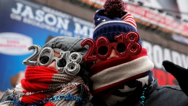 An early gathering of revellers in New York's Times Square wrapped up against the freezing cold