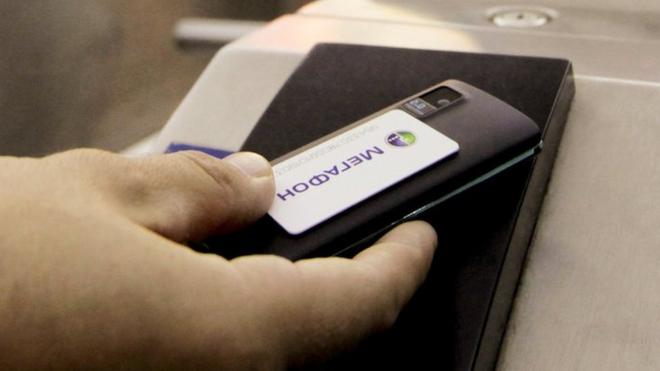 Mobile payment. A cell phone being used to pay for a metro train ticket. The handset is fitted with a smart card that allows near-field communication (NFC), a contactless technology that enables the handset to communicate with the ticket barrier