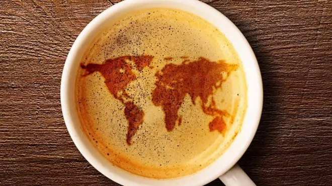 Une carte du monde reflétée dans une tasse de café