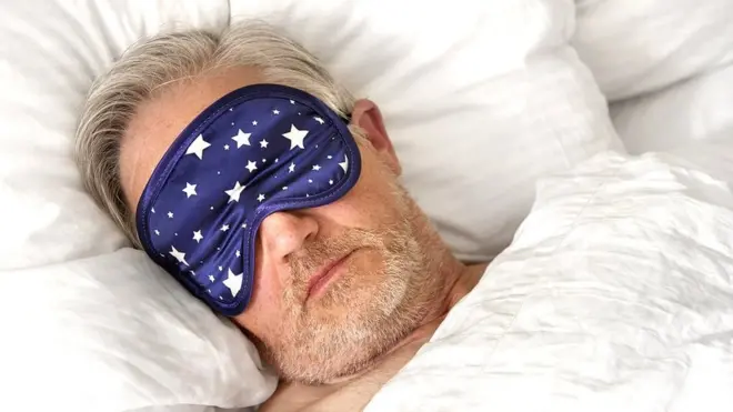 Man in bed wearing an eye mask