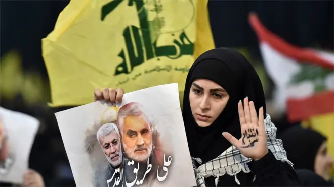 Hezbollah supporter holds up a photo of Abu Mahdi al-Muhandis and Qasem Soleimani at a rally in Beirut, Lebanon (5 January 2020)