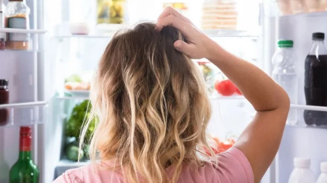 รูปผู้หญิงเกาหัวยืนเปิดตู้เย็น