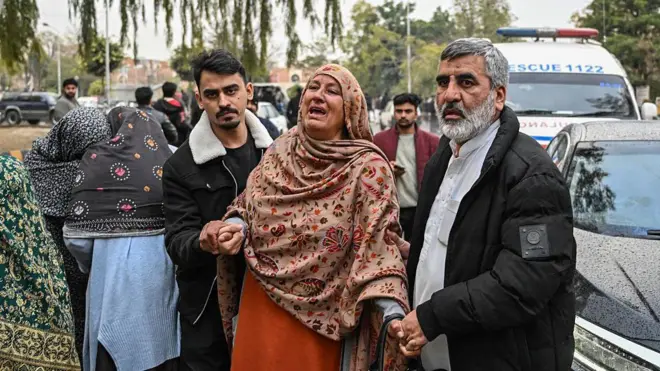 Saldırıdan etkilenen yerel giysili kadın ve erkekler ağlıyor ve birbirine destek oluyor