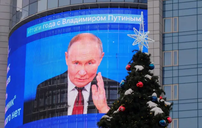 An electronic screen shows an image of Russian President Vladimir Putin at his press conference