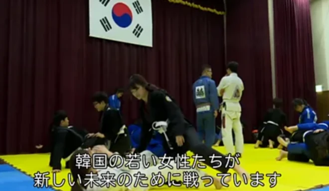 格闘技を練習する女性たち。背後には韓国の国旗が掲げられている