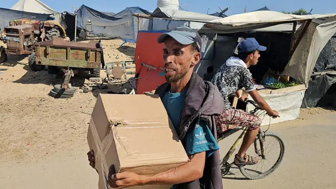 صورة لرجل يحمل صندوق مساعدات من مؤسسة غزة الإنسانية.