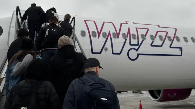 Ludzie wsiadają do samolotu Wizz Air w mglisty poranek na lotnisku w Balicach koło Krakowa, w Polsce, 27 listopada 2024 r.