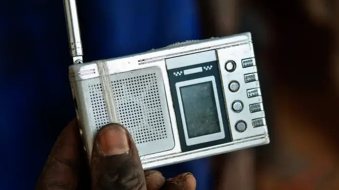 A hand holds a small radio receiver