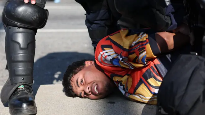 Demonstrant leži na zemlji, okružen policajcima 