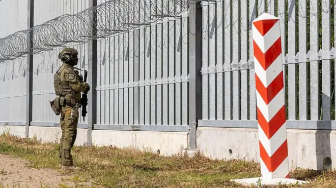 Солдат польської прикордонної служби стоїть на варті перед прикордонною стіною