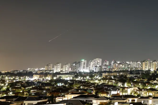 يضيء وميض من الضوء السماء خلال هجوم صاروخي من إيران باتجاه إسرائيل كما يُرى من عسقلان