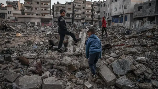 Palestinian boys are seen in the rubble of a building destroyed by an Israeli attack in Rafah, Gaza on 3 January 2024