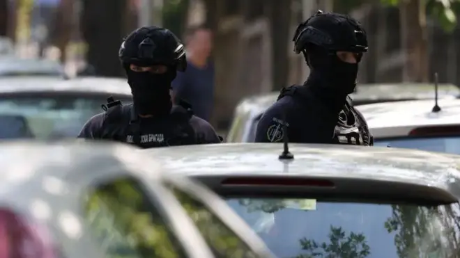 Dvojica policajaca u punoj opremi ispred automobila