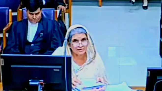 A woman wearing a white sari and flanked by lawyers deposing in a court in the Indian state of Madhya Pradesh