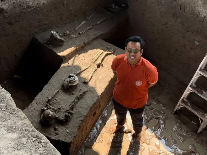 วรรณพงษ์ ปาละกะวงษ์ ณ อยุธยา นักโบราณคดีชำนาญการ ยืนคู่กับโครงกระดูกมนุษย์ยุคก่อนประวัติศาสตร์จากแหล่งขุดค้นโนนพลล้าน