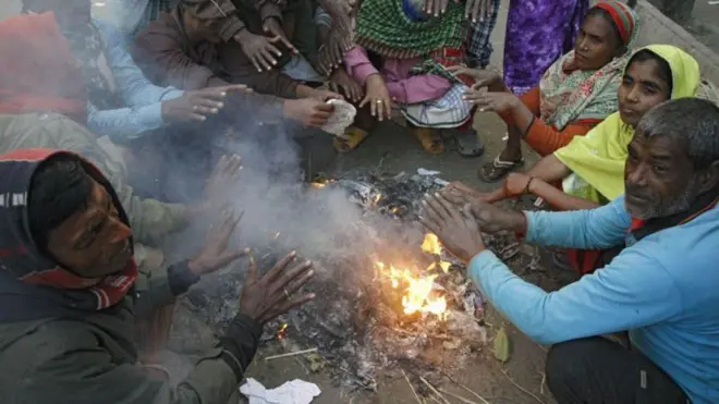 আগুন জ্বালিয়ে তাপ পোহাচ্ছেন অনেকে