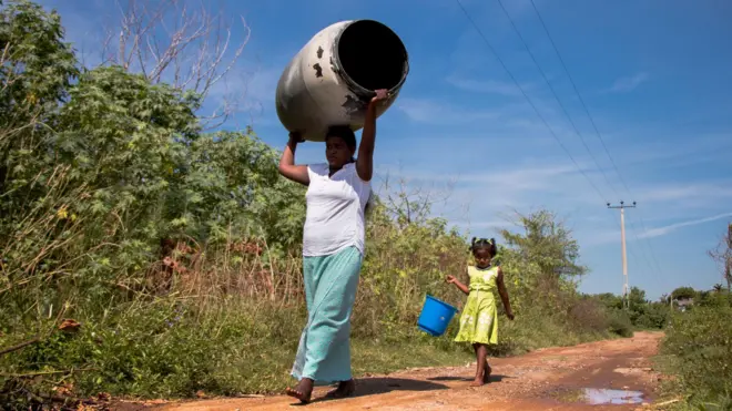 ශ්‍රී ලංකාවේ පුරෝකථනය කර ඇති නියඟයට පෙර කාන්තාවක් සහ දරුවෙකු හිස් ජල භාජන රැගෙන යති.