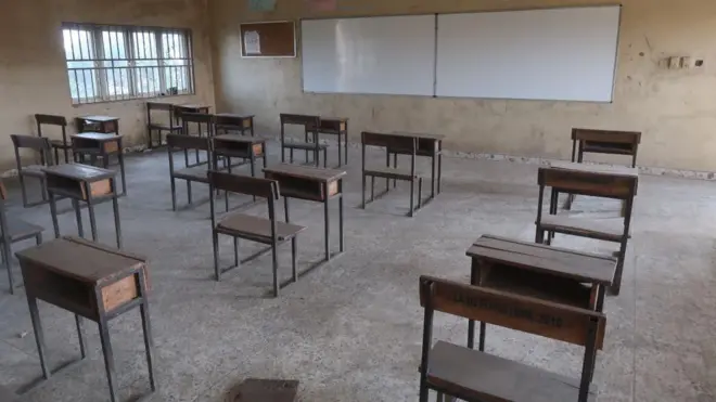 Picture of classroom wey show empty chairs and desks.