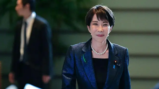 紺色のスーツに真珠のネックレスをしてほほえんでいる高市首相