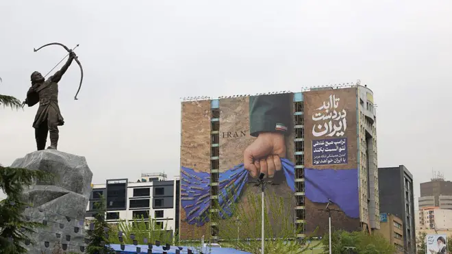 Bir bina yüzüne yapılan görselde Basra Körfezi ve Umman Denizi'ni bağlayan Hürmüz Boğazı'nı tutan İran bayraklı bir el görünüyor. Görselde Farsça Hürmüz'ün İran kontrolünde kalacağına dair mesaj yer alıyor.