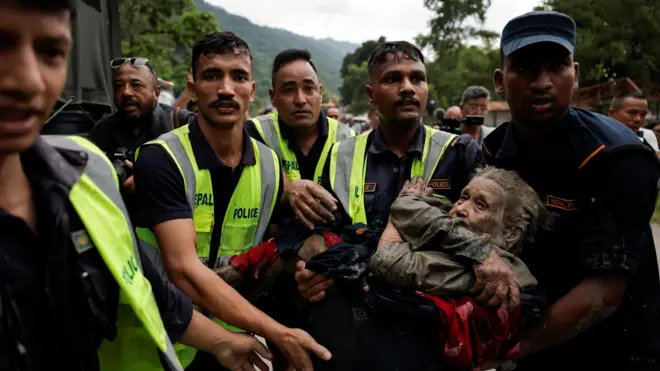 Policiais carregam um sobrevivente para um local mais seguro após uma enxurrada repentina em Trishuli, no Nepal