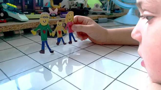 ilustracija - dete drži od kartona napravljenu porodicu