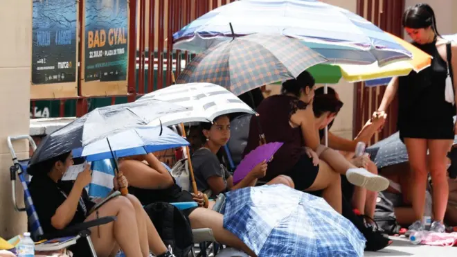 Several pipo dey take shelter from di heat under umbrellas for Murcia for south-eastern Spain