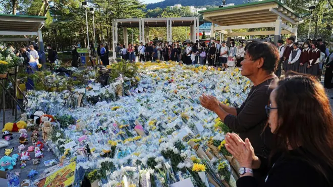 People queue to place flowers at a makeshift memorial near Wang Fuk Court housing estate to pay tribute to victims of the deadly fire at the housing complex, in Tai Po, Hong Kong, China, December 1, 2025