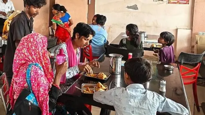 Des convives mangent à plusieurs tables dans un café minable.