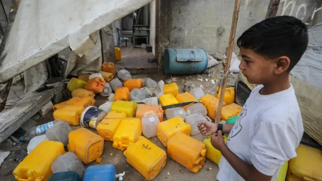 A Palestinian boy inspects the site of an Israeli strike that killed 10 Palestinians, including six children, who were queueing at a water distribution point, in Nuseirat refugee camp, central Gaza (13 July 2025)