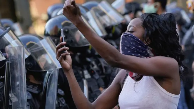 Woman with mobile phone in front of police lines at US demo