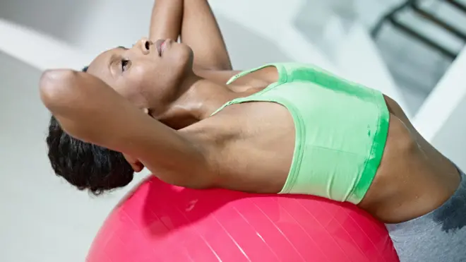 Mujer haciendo abdominales con un balón suizo