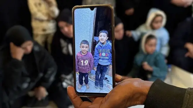 عکس دو پسر خردسال که در حمله روز شنبه اسرائیل کشته شدند. عکس آنها روی صفحه یک موبایل توسط یک فرد نشان داده شده است