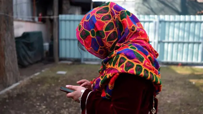 یوه افغانه مېرمن موبایل ته ځيره ده.