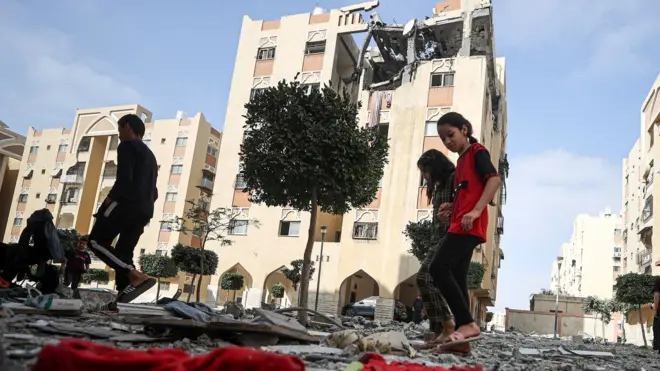 Palestinian children walk past a damaged apartment building in Khan Younis where Islamic Jihad commander Ali Hassan Ghali and two other people were killed in an Israeli strike (11 May 2023)