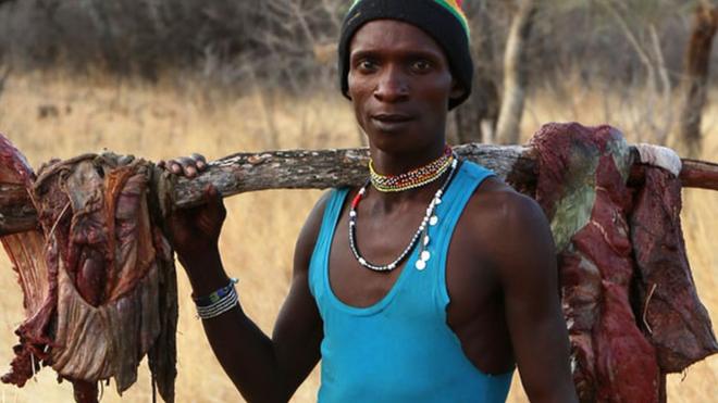 Hadza man carrying meat on a stick