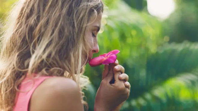 Mujer oliendo flor.