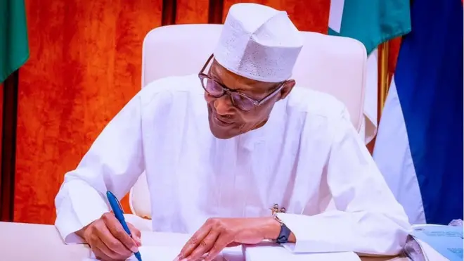 President Buhari as e dey sign di PIB into law