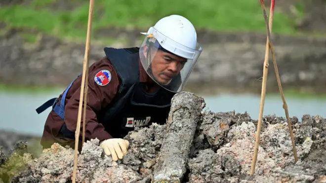 Un démineur du Centre cambodgien d'action contre les mines examine une munition non explosée dans la province de Svay Rieng, au Cambodge.