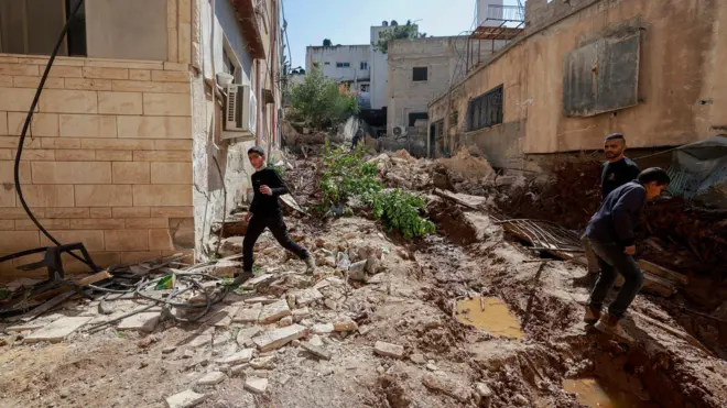 فلسطينيون يتفقدون الدمار الذي أعقب غارة إسرائيلية في يوم سابق في الحي الشرقي لمدينة جنين بالضفة الغربية المحتلة، في 11 مارس/آذار 2025.