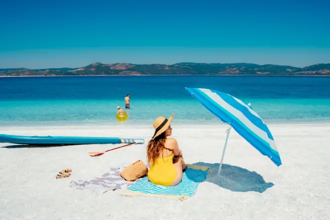 Bir kadın plajda oturuyor