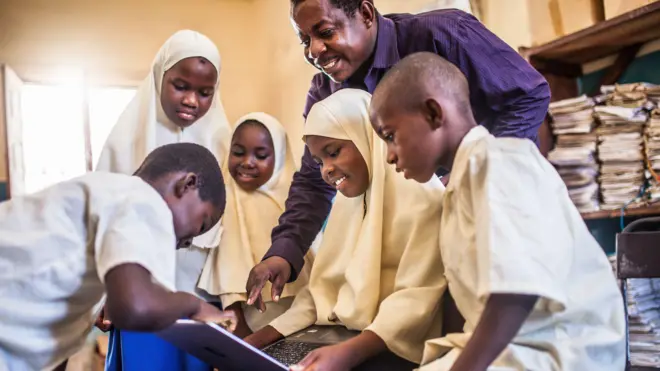 African children using a laptop inside classroom