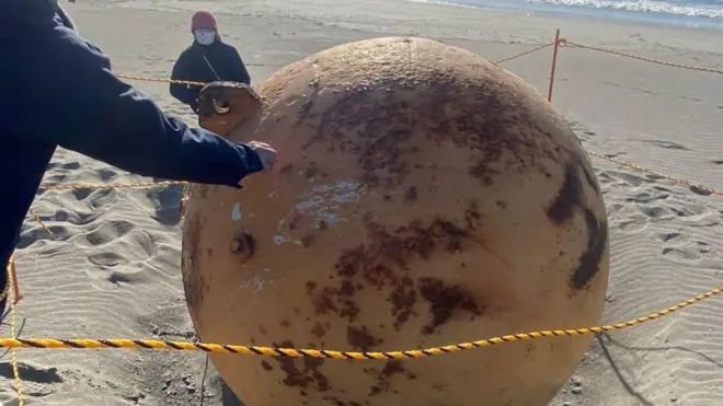 Esfera metálica na areia da praia