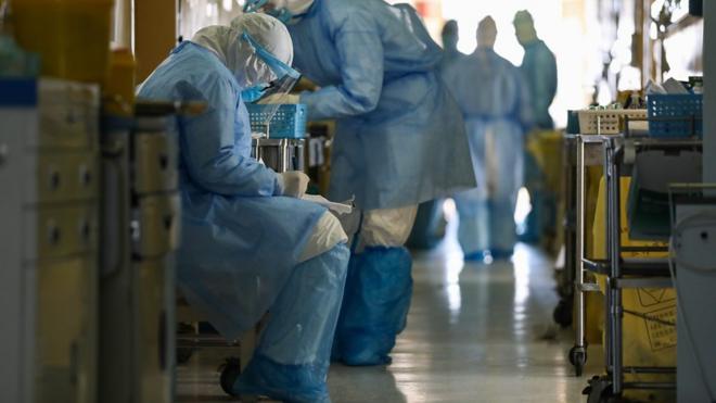 武汉某收治新冠肺炎患者医院内一名身穿全身防护衣的护士坐在走廊旁边填写文件（16/2/2020）