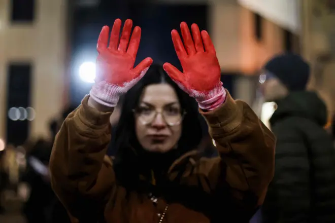 22 Aralık 2024'teki protesto sıradında kırmızıya boyanmış eldivenler giyinen bir kadın.