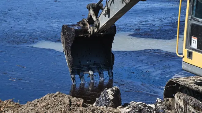 экскаватор чистит воду от нефтяных загрязений